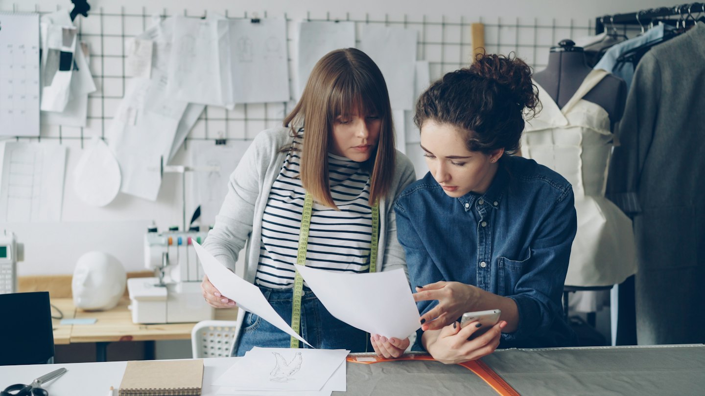 Due designer collaborano su schizzi a un banco da lavoro in studio.