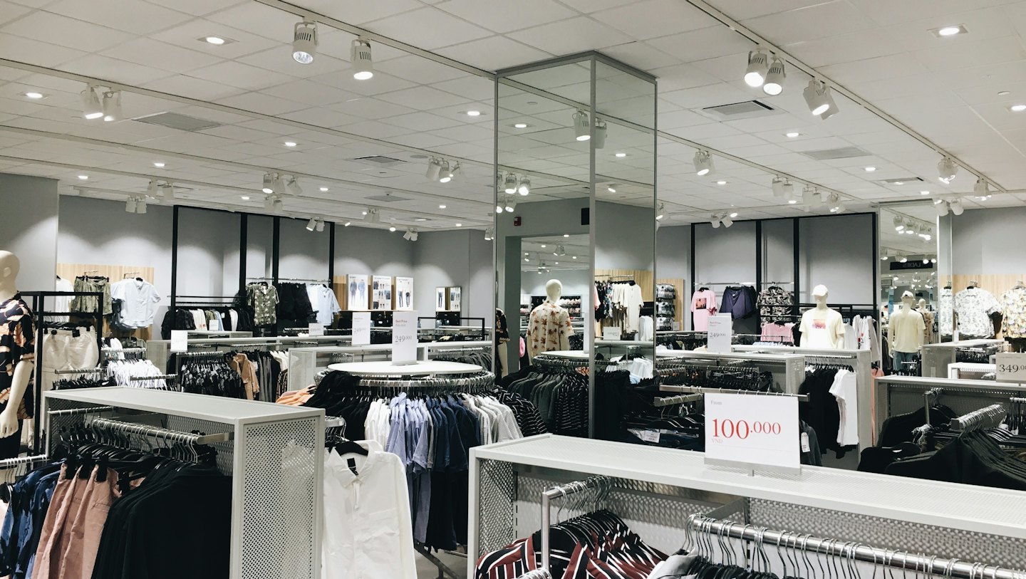 Interno di un negozio di abbigliamento con scaffali di vestiti e manichini.
